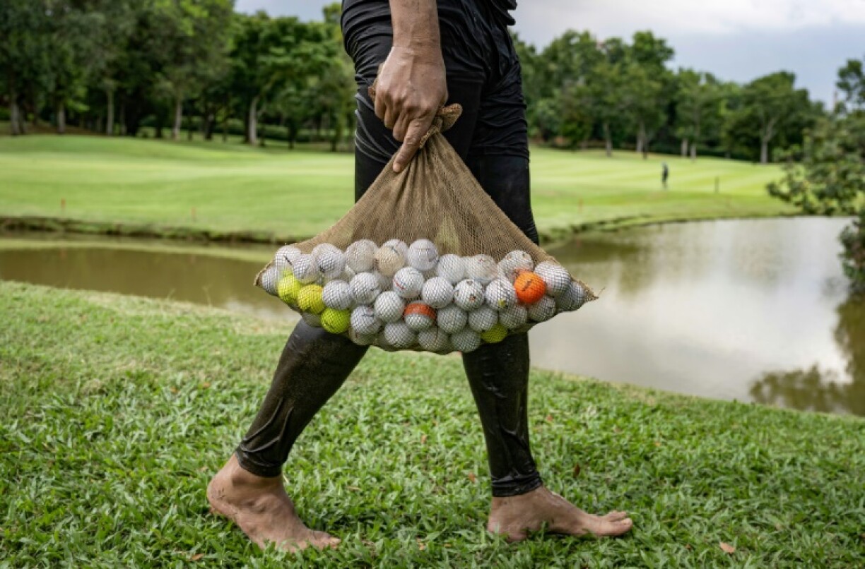 Sumadi Ibrahim carrying golf balls he recovered from a pond at a course in Shah Alam on the outskirts of Kuala Lumpur