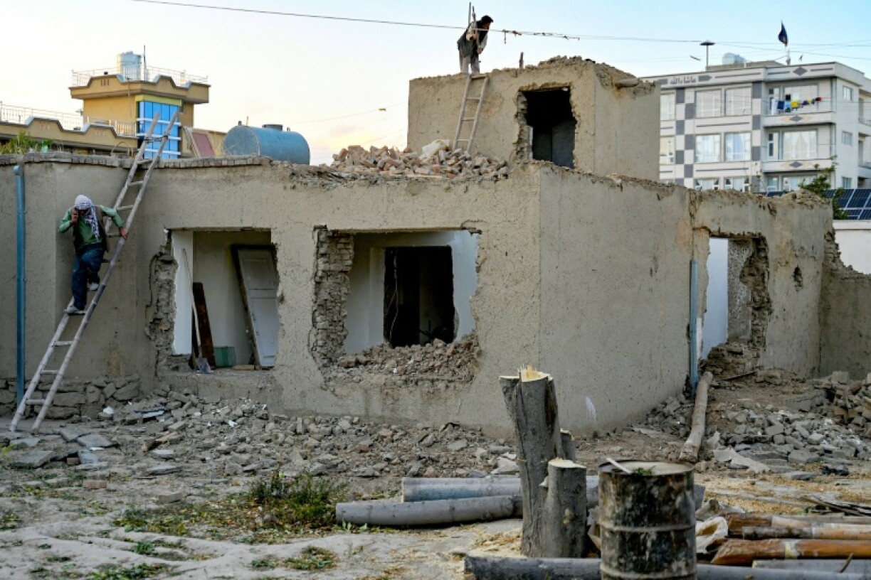 Afghan construction workers demolish a house under a redevelopment plan by Taliban authorities