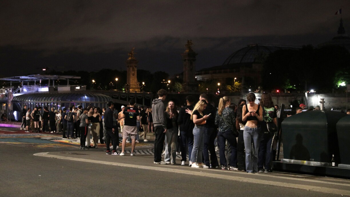 People stand on the banks of the Seine River past the 11pm Covid-19 curfew, early on June 12, 2021, after people gathered nearby at Les Invalides for an unauthorized outdoor party.
