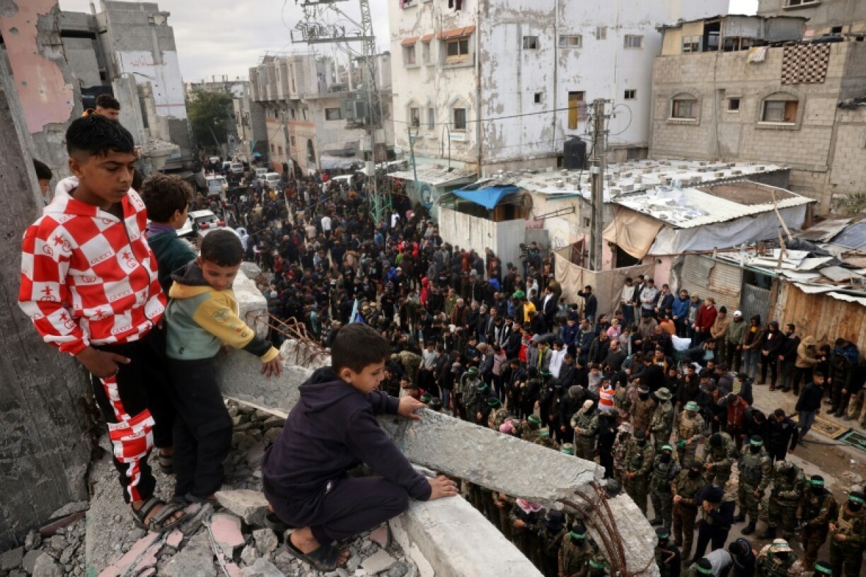 Children look on as Hamas fighters and mourners perform the noon prayer during the funeral for top Hamas commander Marwan Issa in central Gaza's Bureij refugee camp