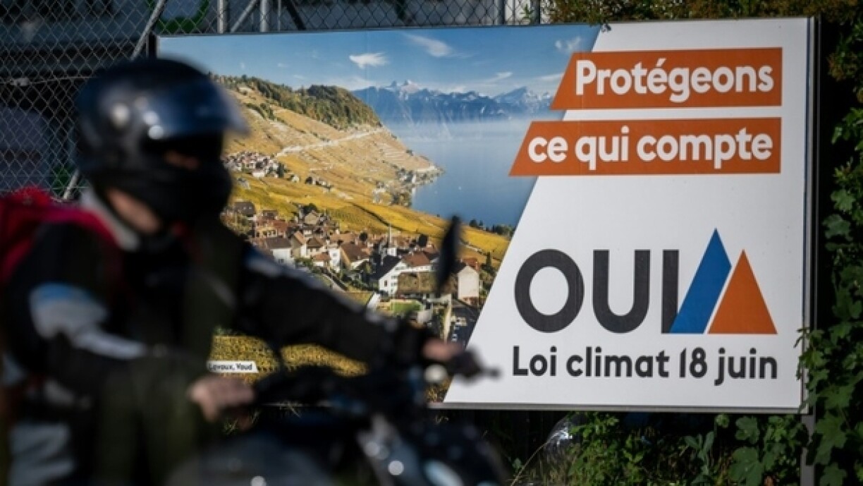 Un motard passe devant une affiche électorale indiquant