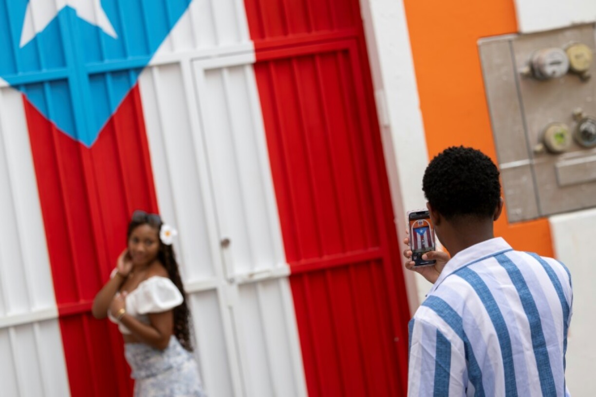 A man photographs a woman in front of a Puerto Rican flag mural in Old San Juan, Puerto Rico on May 13, 2025
