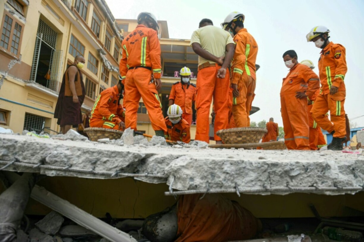 Rescue workers try to retrieve the body of a victim trapped in the rubble of a damaged temple in Mandalay