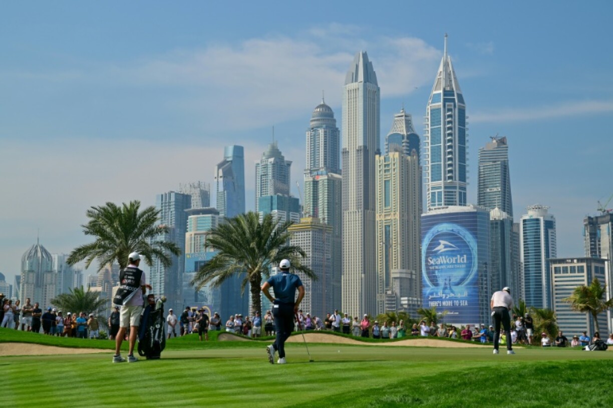 Northern Ireland's Rory McIlroy (R) putts on the eighth hole during the first day of the Dubai Desert Classic