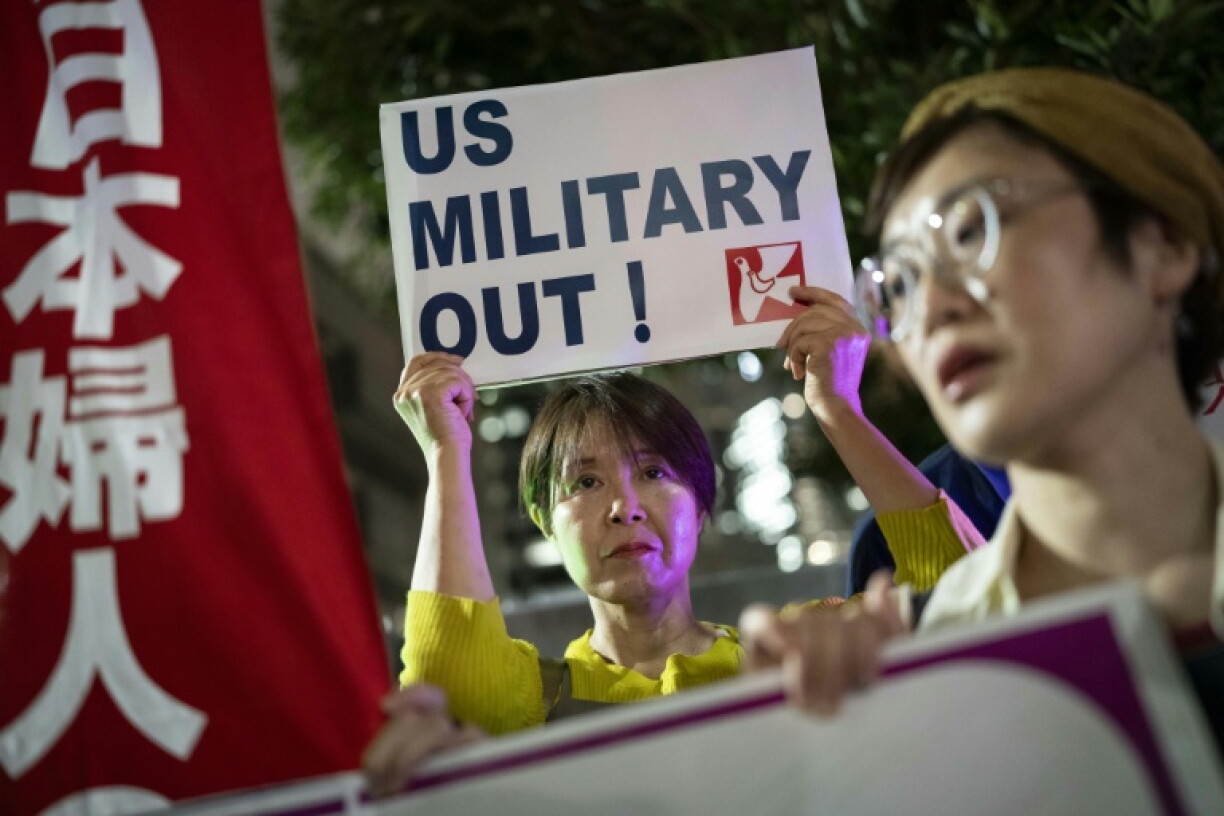 A woman holds up a placard reading 'US military out' during a protest against the killing of a woman in Okinawa allegedly committed by a US Marine Corps member, in front of the Prime Minister's Office in Tokyo on October 5, 2026. A woman's murder allegedly committed by a US Marine in Okinawa is a "heinous crime", Japan's premier said on October 5, as the new accusation of violence involving American forces sparked public outrage.