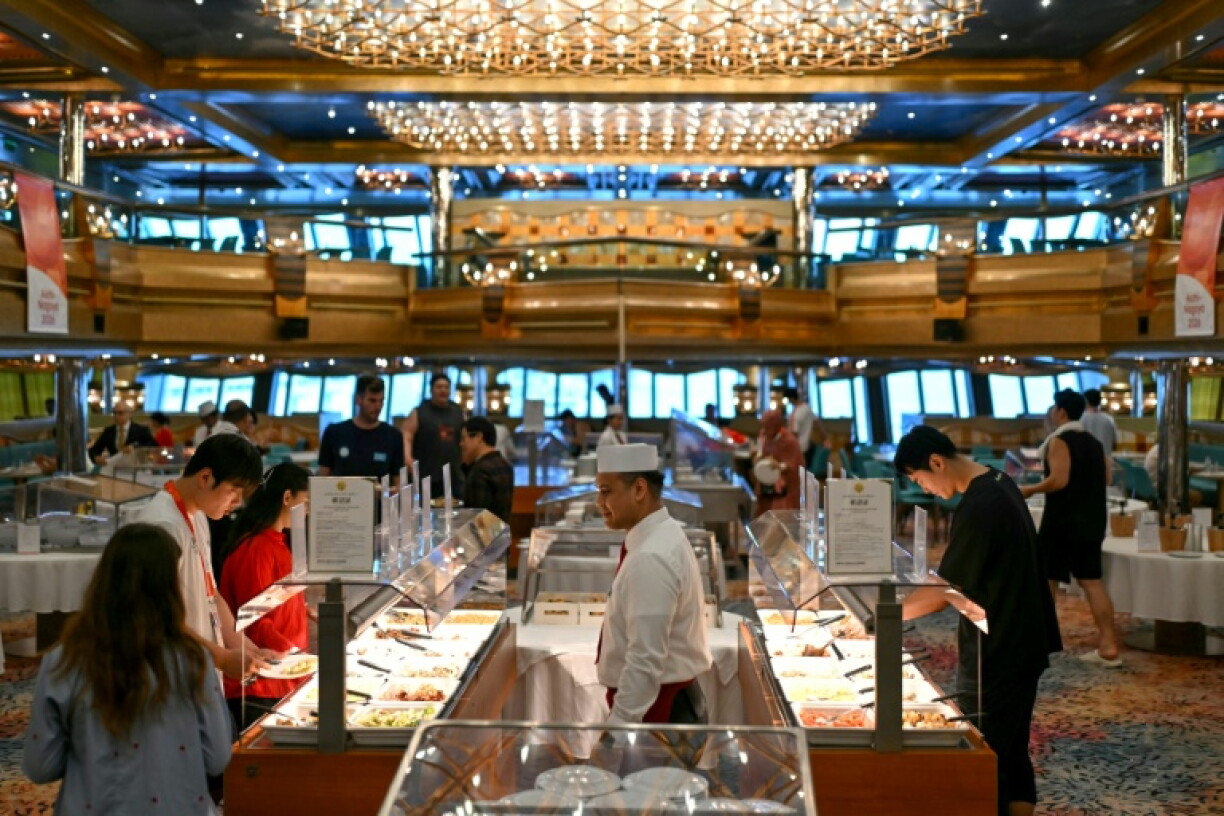 Athletes pick up food at a buffet in a dining room on the Costa Serena cruise ship