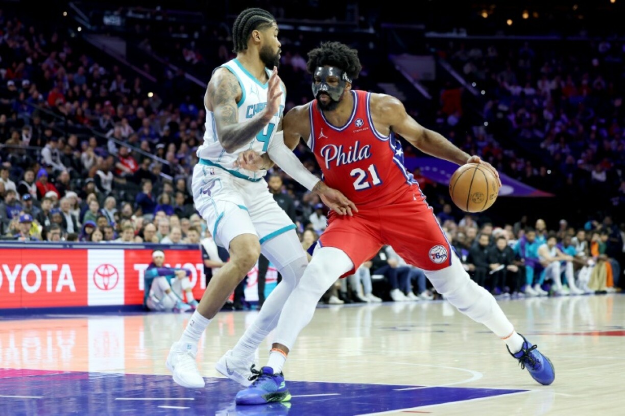 Philadelphia 76ers star Joel Embiid, wearing a protective face mask, drives against Nick Richards in the Sixers' NBA victory over the Charlotte Hornets