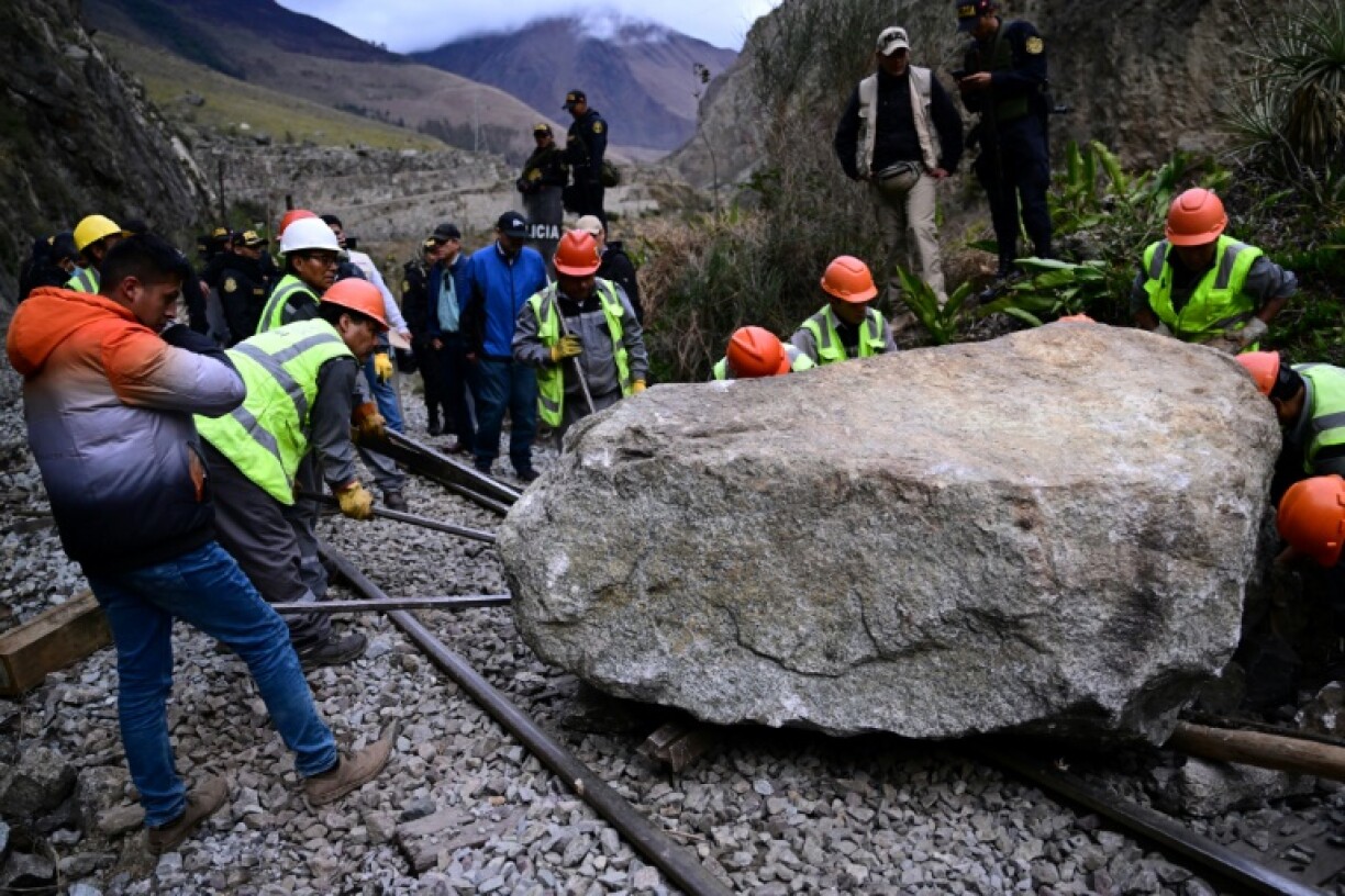 Des travailleurs tentent de retirer un rocher bloquant les voies du train de Machu Picchi, au Pérou, le 17 décembre 2022