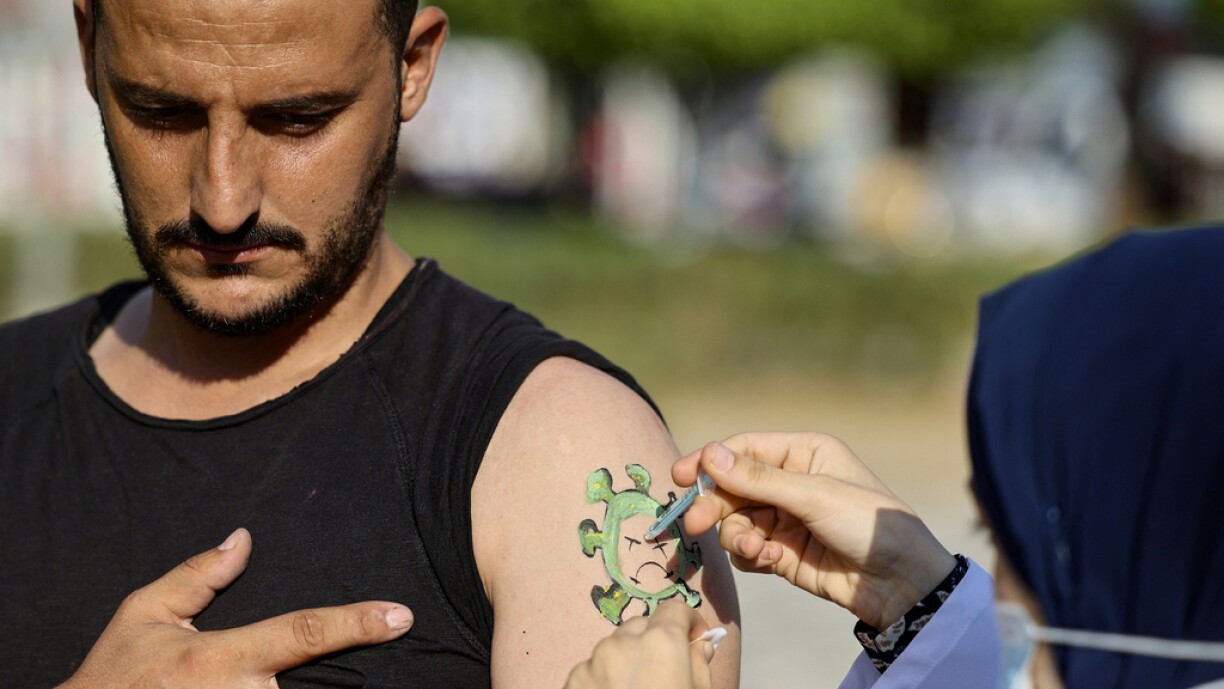 A Palestinian man receives a doze of the Sputnik-V vaccine against the coronavirus, on an arm on which an artist painted a virus, during a vaccination campaign organised by the health ministry, in Gaza City, on September 1, 2021.