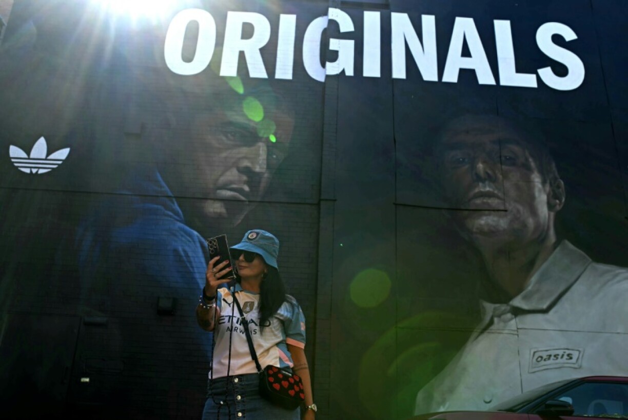 An Oasis fan takes a selfie in front of mural of the band's Gallagher brothers in their Manchester hometown