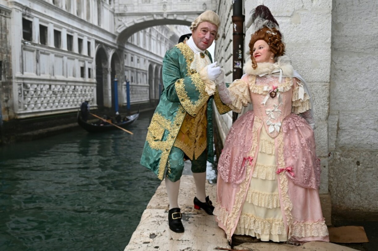 Des carnavaliers portant des costumes d'époque posent devant le Pont des Soupirs lors de la pré-ouverture du carnaval de Venise, le 27 janvier 2024.