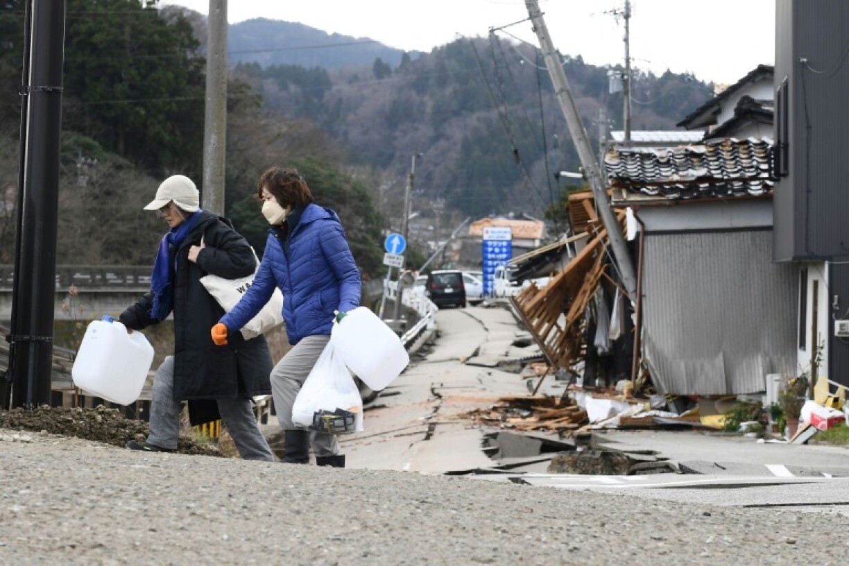 Des habitants transportent des bidons d'eau après un séisme meurtrier, à Wajima au Japon le 5 janvier 2024.