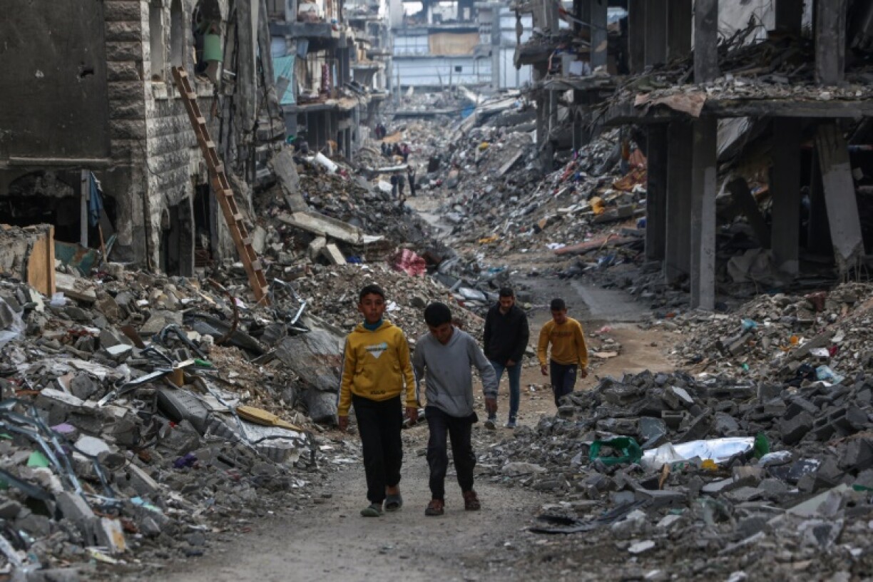 Palestinians walk in a war-ravaged neighbourhood in Beit Lahia in the northern Gaza Strip