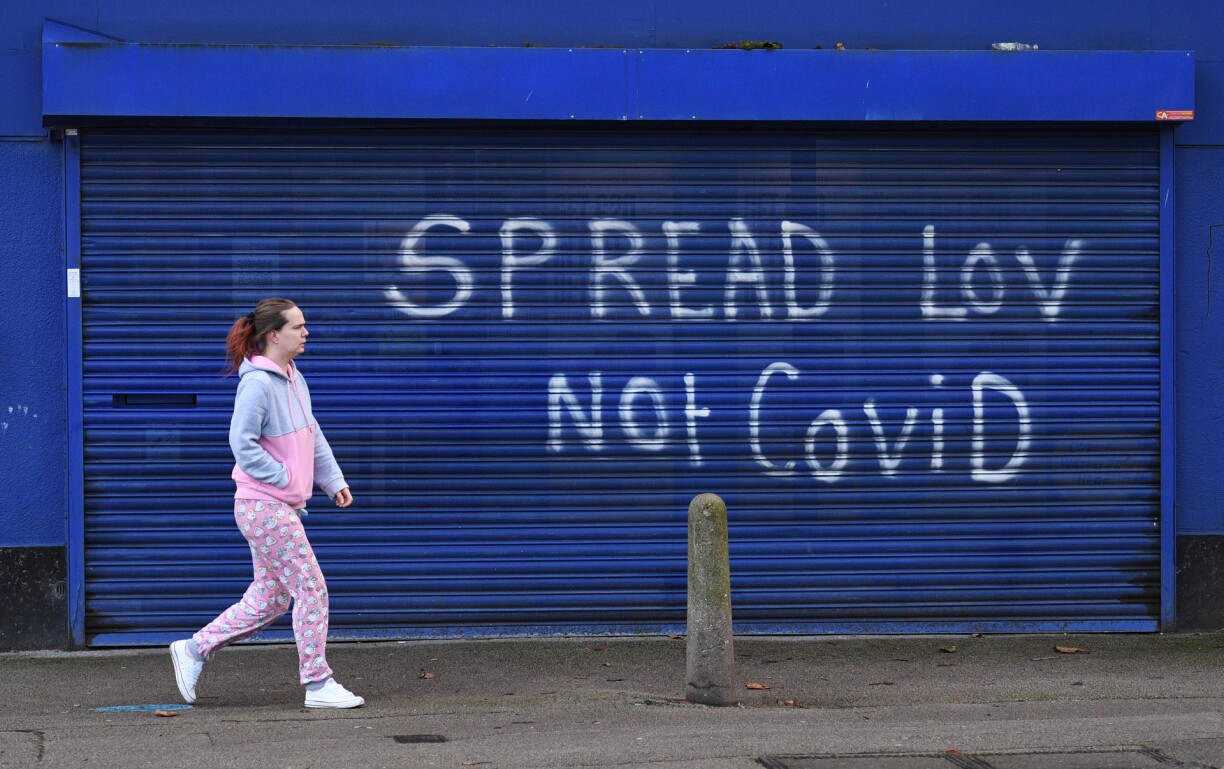 A pedestrian walks past graffiti reading