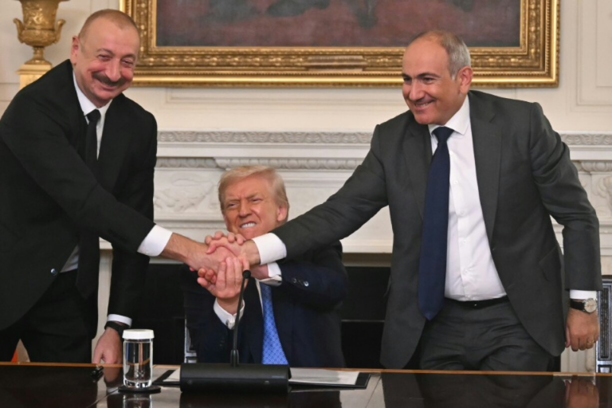Azerbaijani President Ilham Aliyev, left, and Armenia's Nikol Pashinyan shake hands in front of US President Donald Trump