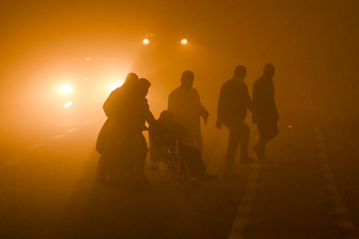 A wheelchair-user is helped across a road in dangerously low visibility in the southern Iraqi city of Basra on Monday.