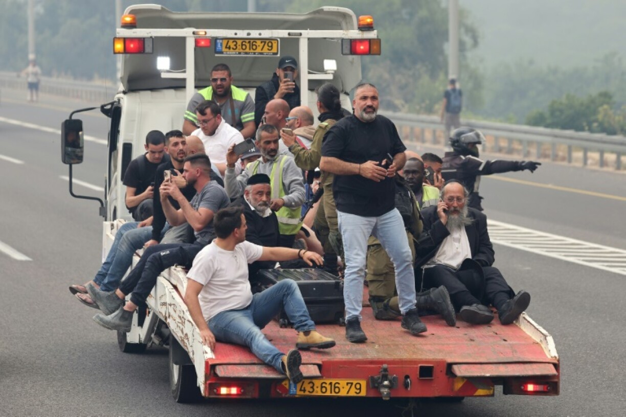 People are evacuated on a recovery vehicle at a highway during a forest fire