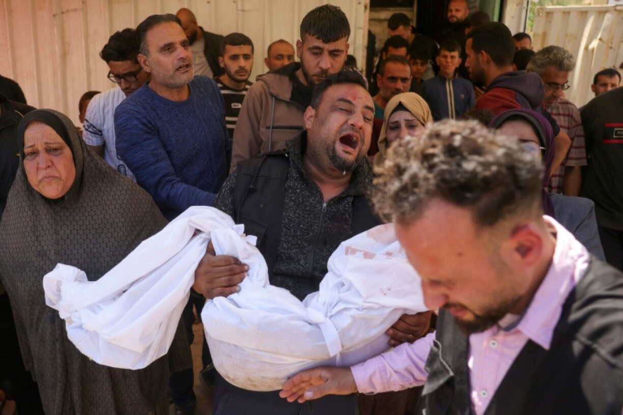 The father of Abir Srour carries the shrouded body of his daughter, killed in an Israeli strike, during her funeral at the Indonesian Hospital in Beit Lahia, northern Gaza