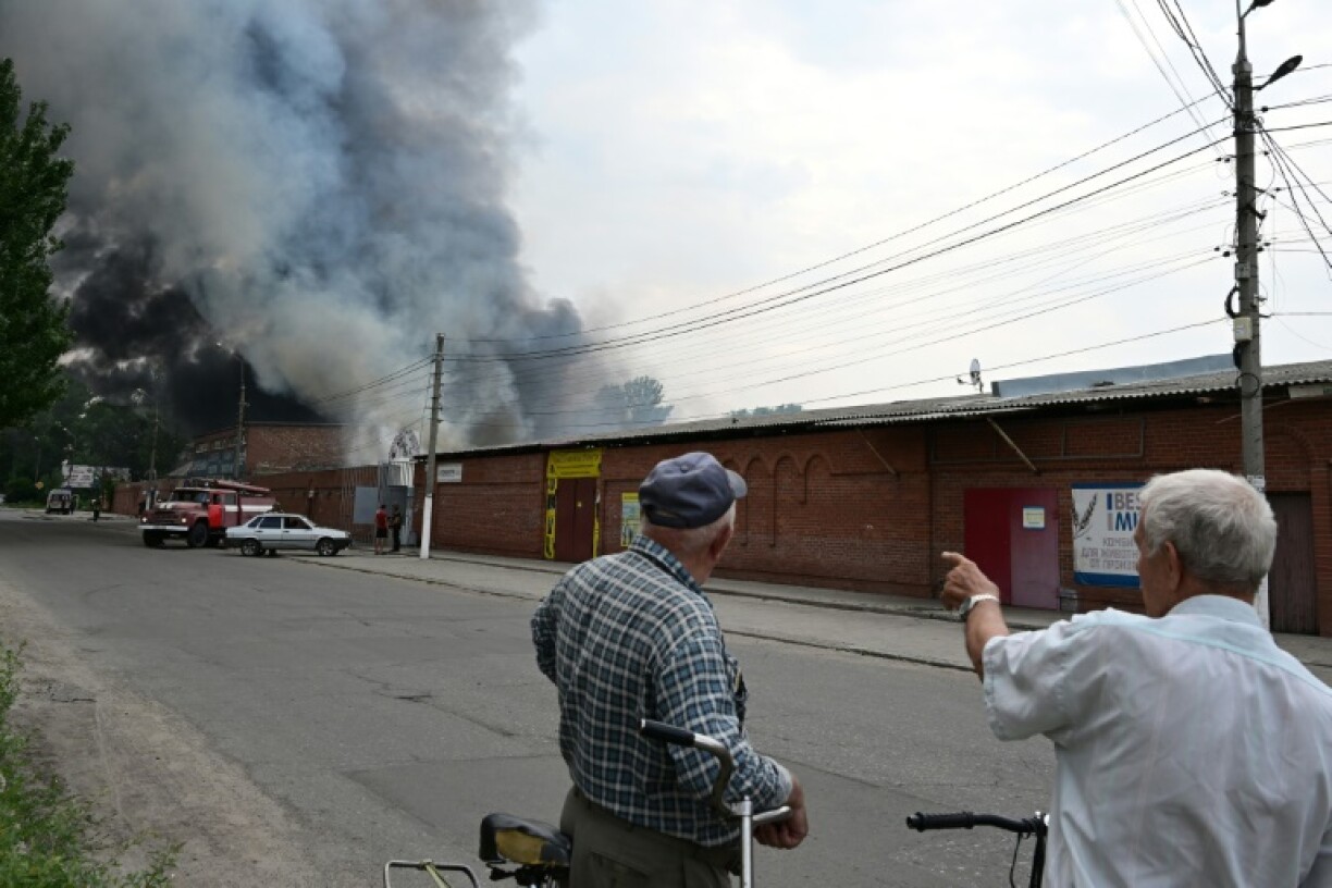 Hommes regardant une fumée s'élever du marché de Sloviansk, en Ukraine, après un bombardement russe, le 5 juillet 2022