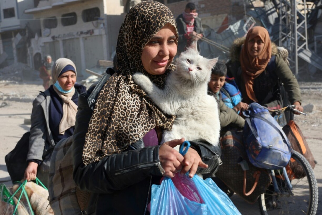 A Palestinian woman carries her cat as displaced people from Beit Lahia arrive in Jabalia in the northern Gaza Strip on December 4, 2024