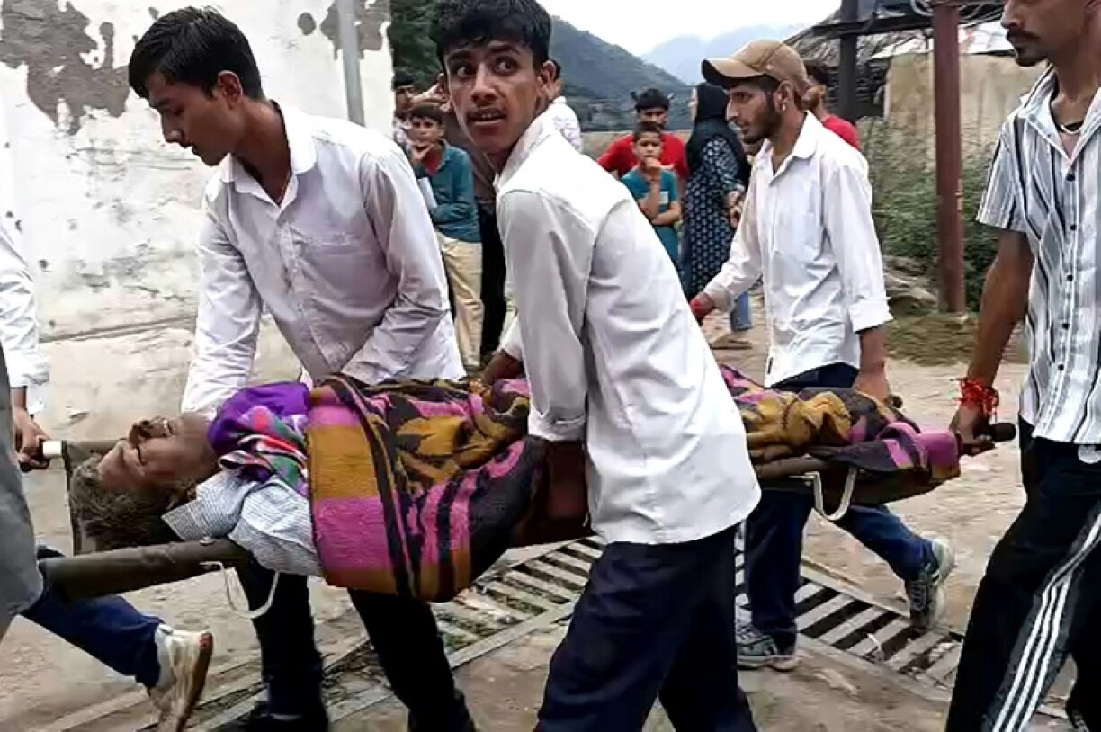 An injured person is carried to a hospital after torrents of water slammed into a Himalayan mountain village in Indian-administered Kashmir