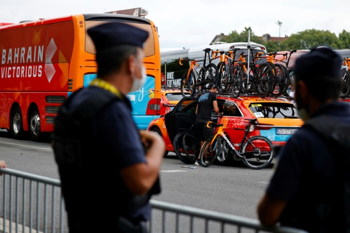 Un policier près du bus et d'une voiture de l'équipe Bahrain le 15 juillet 2021 avant le départ de la 18e étape du Tour de France à Pau