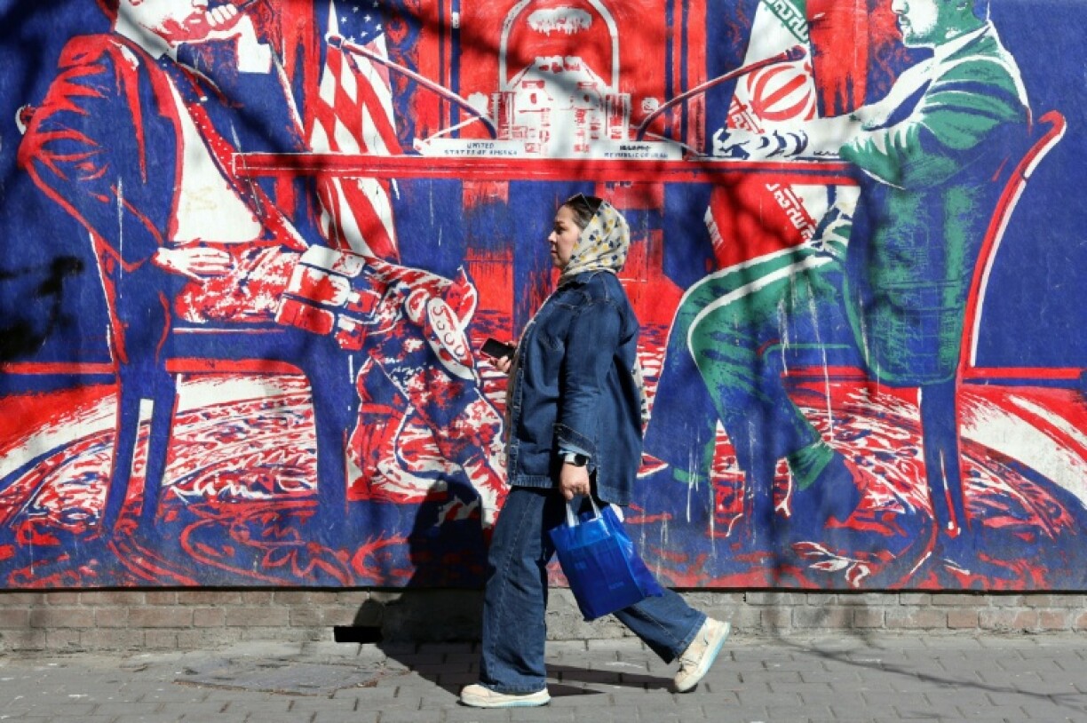 Une Iranienne passe devant un panneau anti-américain représentant des discussions Entre les deux pays, à Téhéran, le 26 février 2026