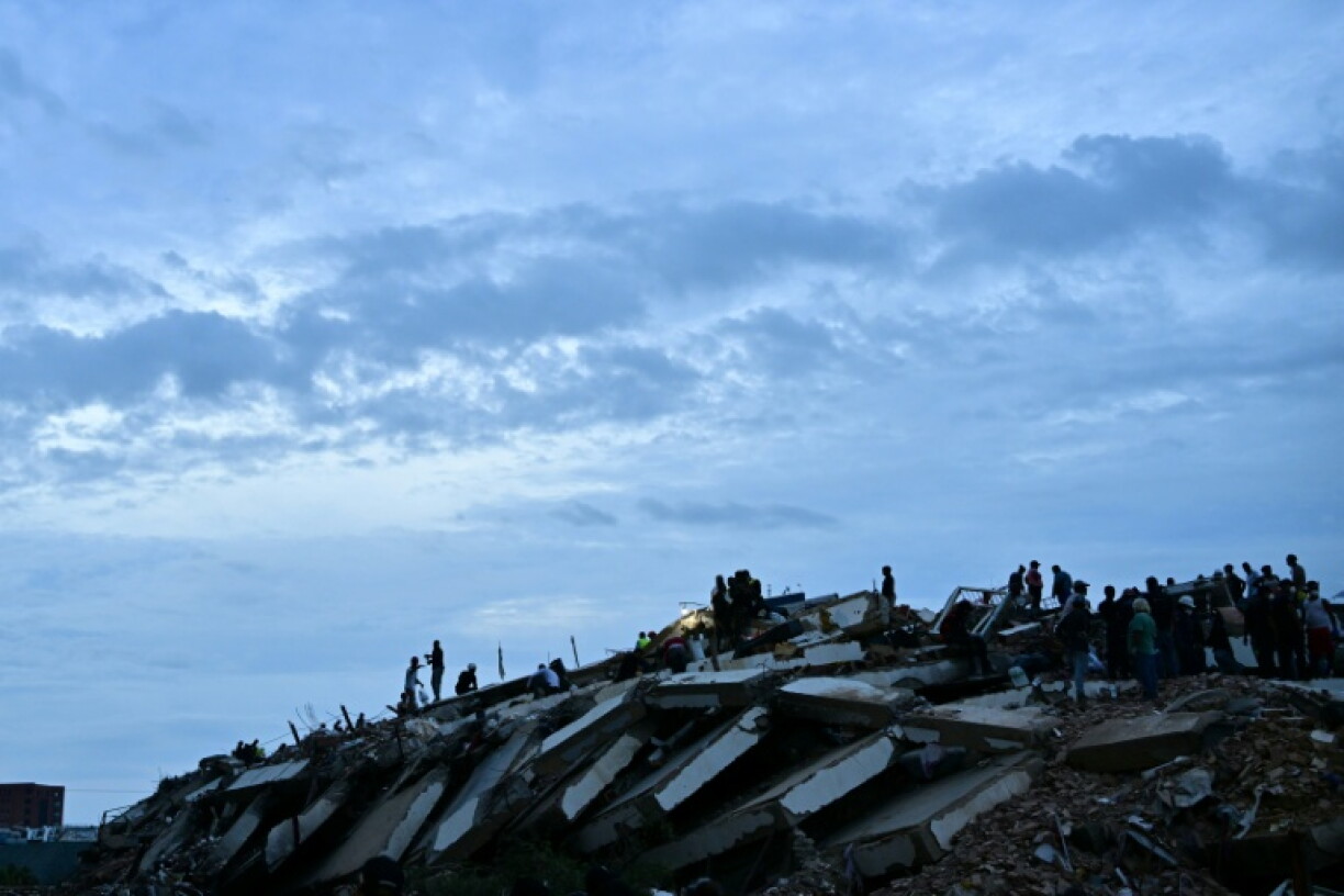 Des secouristes et des bénévoles travaillent dans les ruines d'un immeuble effondré après le double séisme au Venezuela, le 3 juillet 2026 à Caraballeda, dans l’État de La Guaira