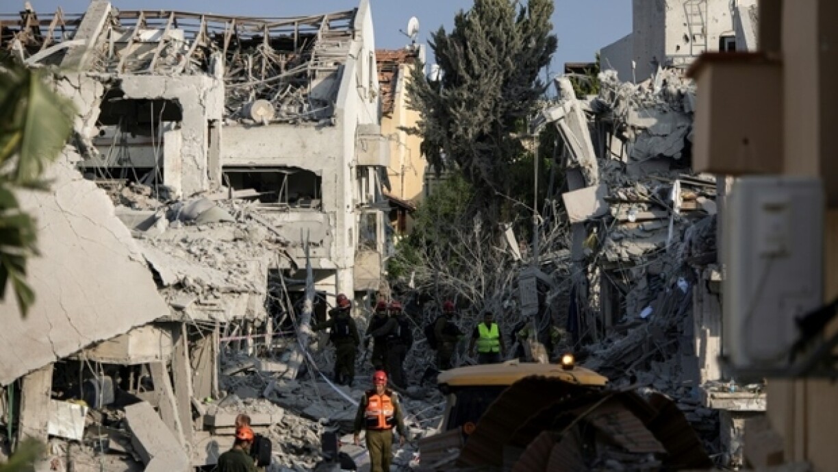 Des secouristes israéliens inspectent un site touché par un missile tiré depuis l'Iran au sud de Tel-Aviv, le 14 juin 2025