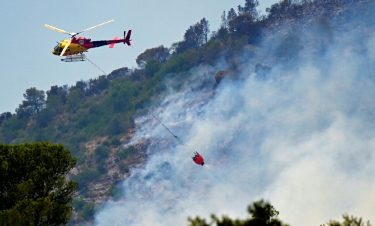 A firefighting helicopter drops water on a forest fire