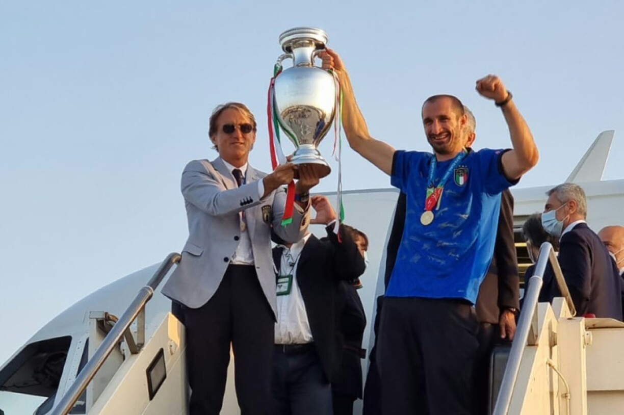 Le sélectionneur de l'Italie Roberto Mancini (g.) et le défenseur central italien Giorgio Chiellini (d.) tenant le trophée du Championnat d'Europe de foot après la victoire de l'Italie lors de la finale de l'EURO 2020 entre l'Italie et l'Angleterre, après leur arrivée à l'aéroport Fiumicino de Rome, le 12 juillet 2021.