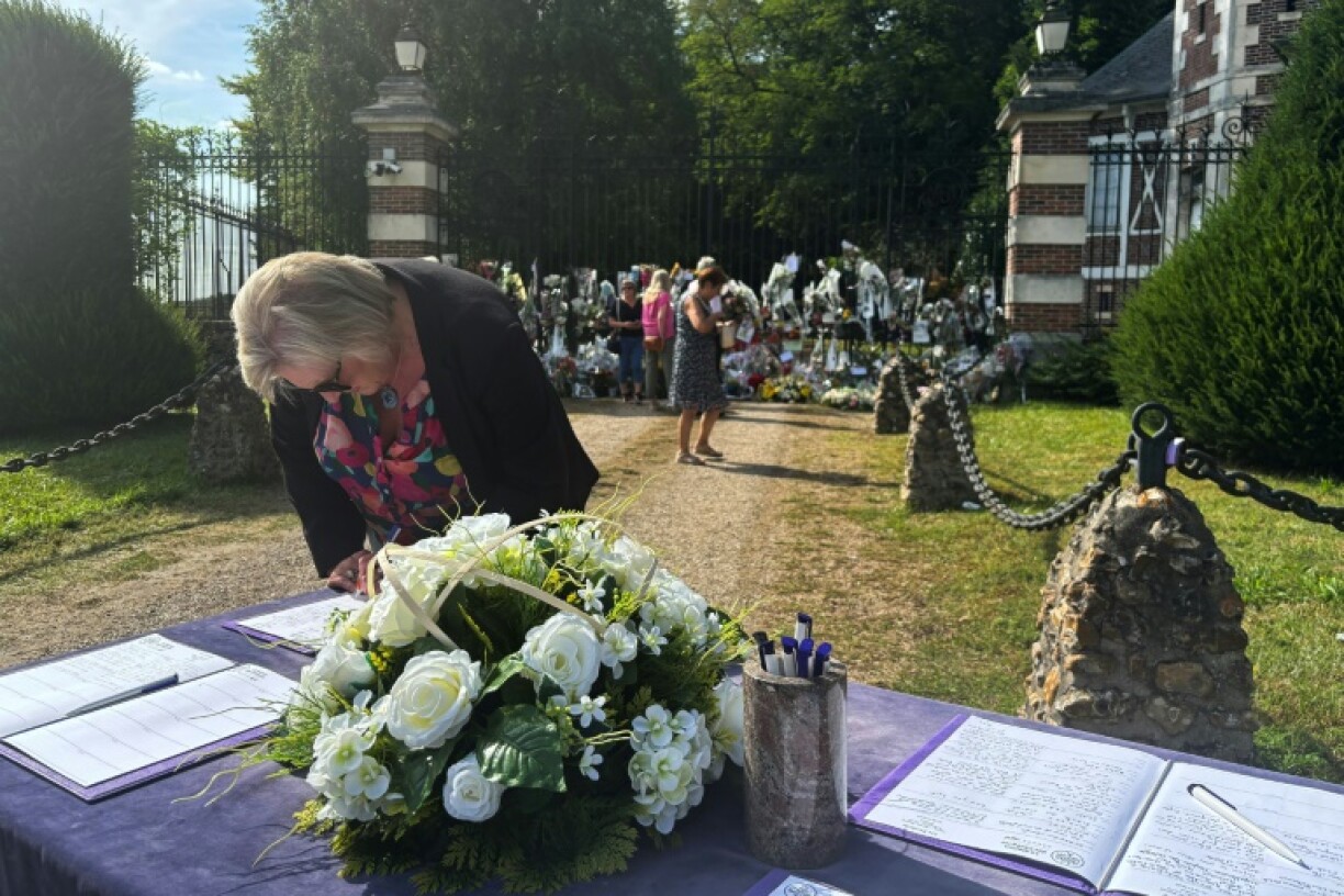Une femme écrit un message sur le registre de condoléances devant la propriété de l'acteur Alain Delon décédé, le 21 août 2024 à Douchy, dans le Loiret