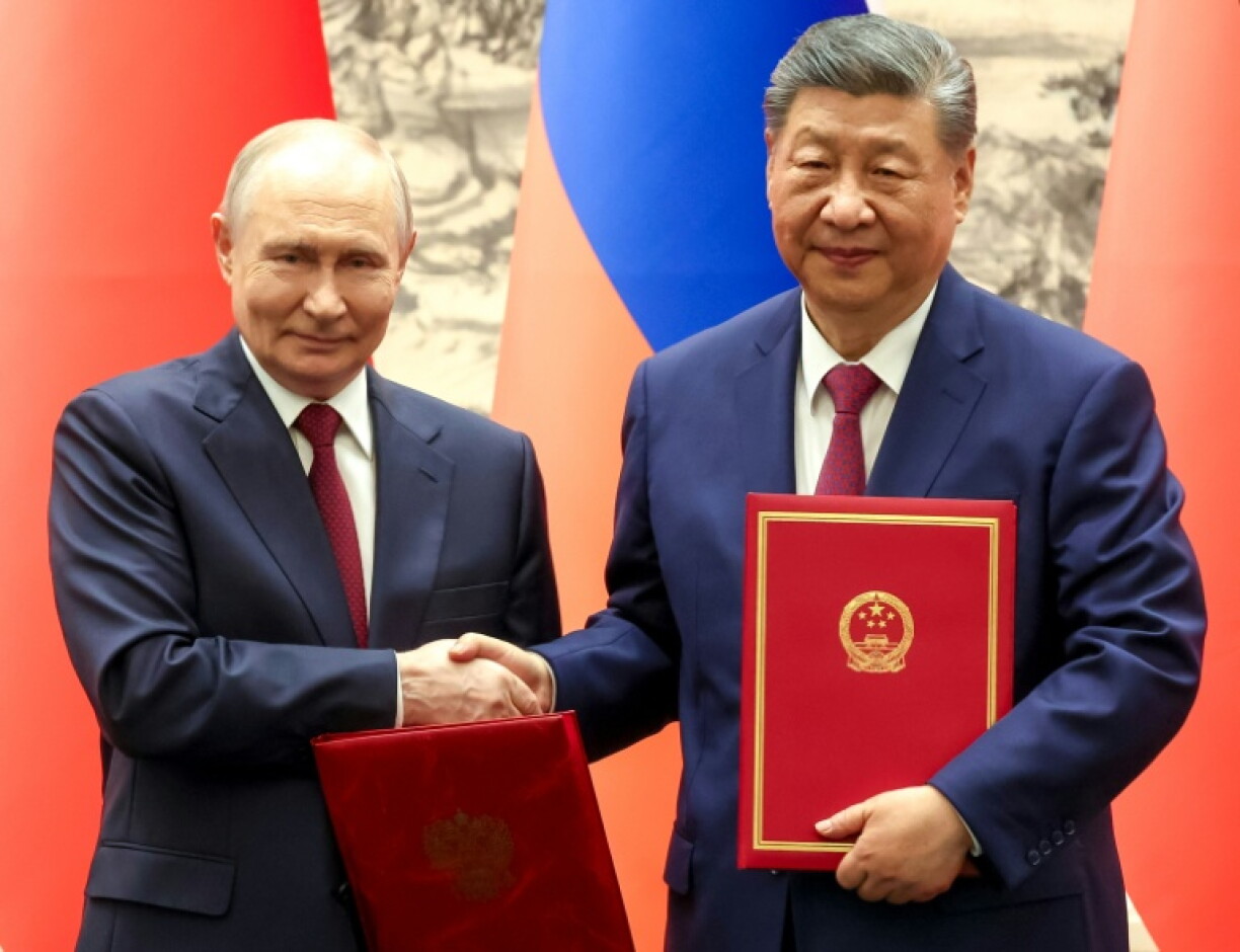 Photo diffusée par l'agence de presse russe Sputnik montrant le président russe Vladimir Poutine (g) et le président chinois Xi Jinping se serrant la main lors d'une cérémonie de signature à Pékin, le 20 mai 2026