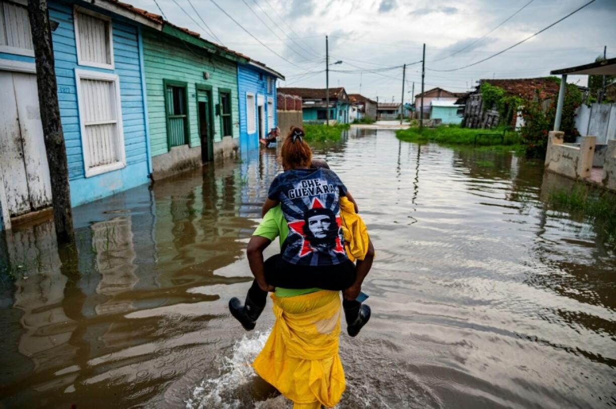 Un homme porte une femme sur son dos dans une zone inondée de Batabano, le 28 août 2023, lors du passage de la tempête tropicale Idalia au large de la pointe ouest de Cuba