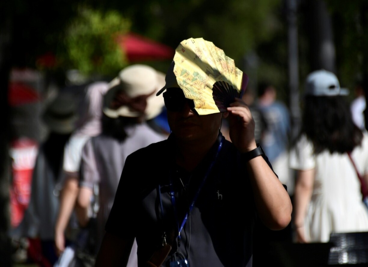 A tourist uses a fan to shield himself from the sun in the Spanish city of Seville last July