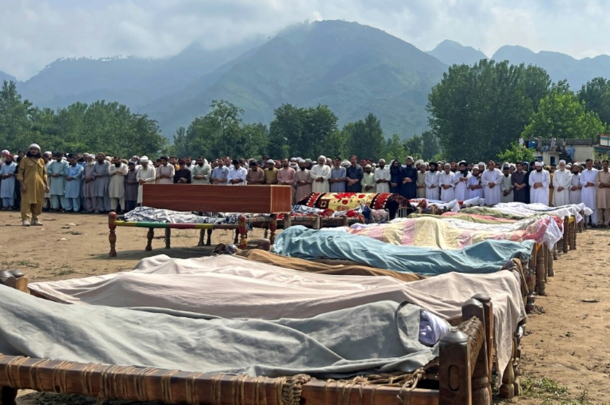 Mourners gather for mass funerals, where bodies wrapped in shawls were laid out on the village ground