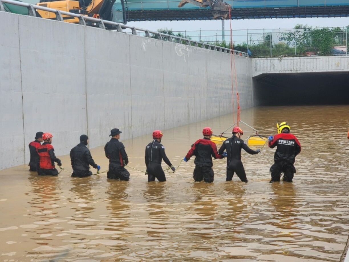 Des secouristes à la recherche de personnes disparues le long d'une route inondée menant à un tunnel souterrain où une quinzaine de voitures ont été piégées par une crue après de fortes pluies à Cheongju, en Corée du Sud, le 16 juillet 2023