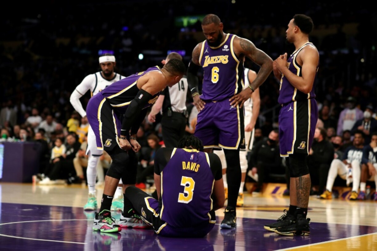 Russell Westbrook (g.), LeBron James (c.) et Talen Horton-Tucker (d.) des Los Angeles Lakers au chevet de leur coéquipier Anthony Davis, au sol, après sa blessure dans le deuxième quart-temps lors du match de NBA entre les Los Angeles Lakers et le Utah Jazz à la Crypto.com Arena le 16 février 2022 à Los Angeles, Californie