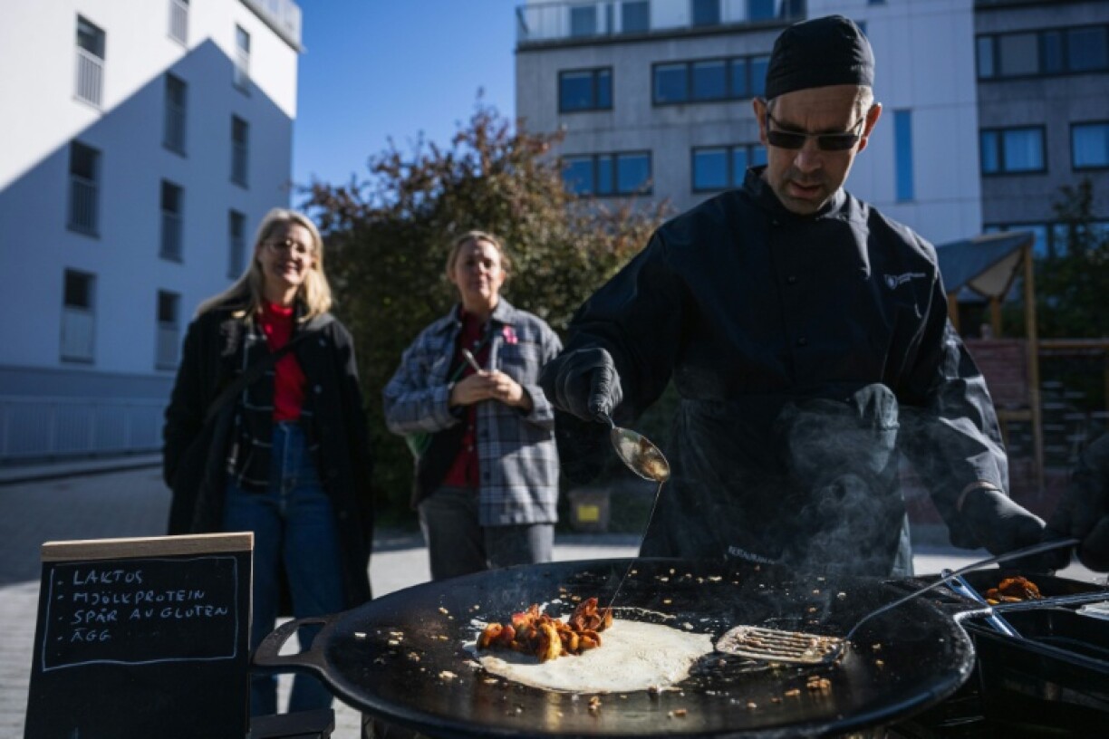 Onlookers watch as workers prepare a dish that can be made under emergency conditions
