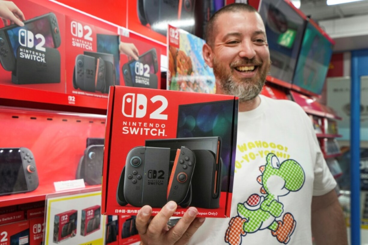 A French customer living in Tokyo smiles as he shows off a Nintendo Switch 2 bought at an electronics retailer