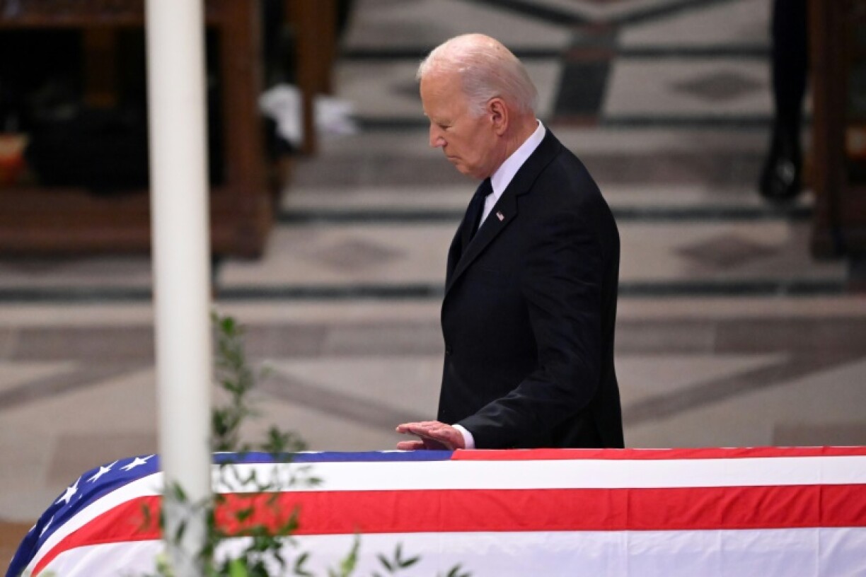 US President Joe Biden touches the casket after delivering the eulogy for former president Jimmy Carter