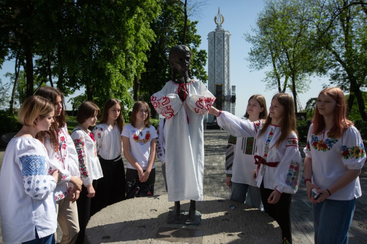 Des enfants posant à côté de la statue qui symbolise les victimes de l'Holodomor, le 18 mai dernier à Kiev.