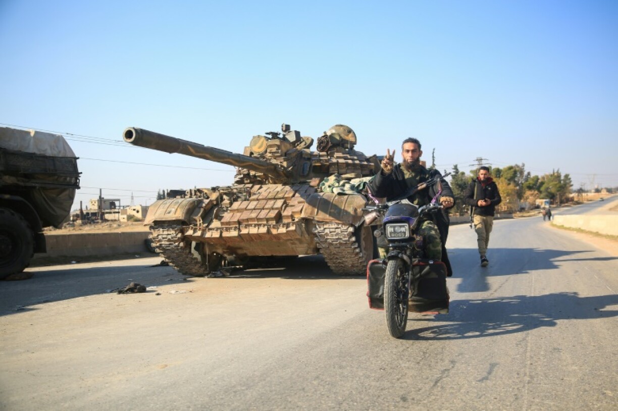 Rebel fighters pass an abandoned army military on the road southeast from Aleppo.