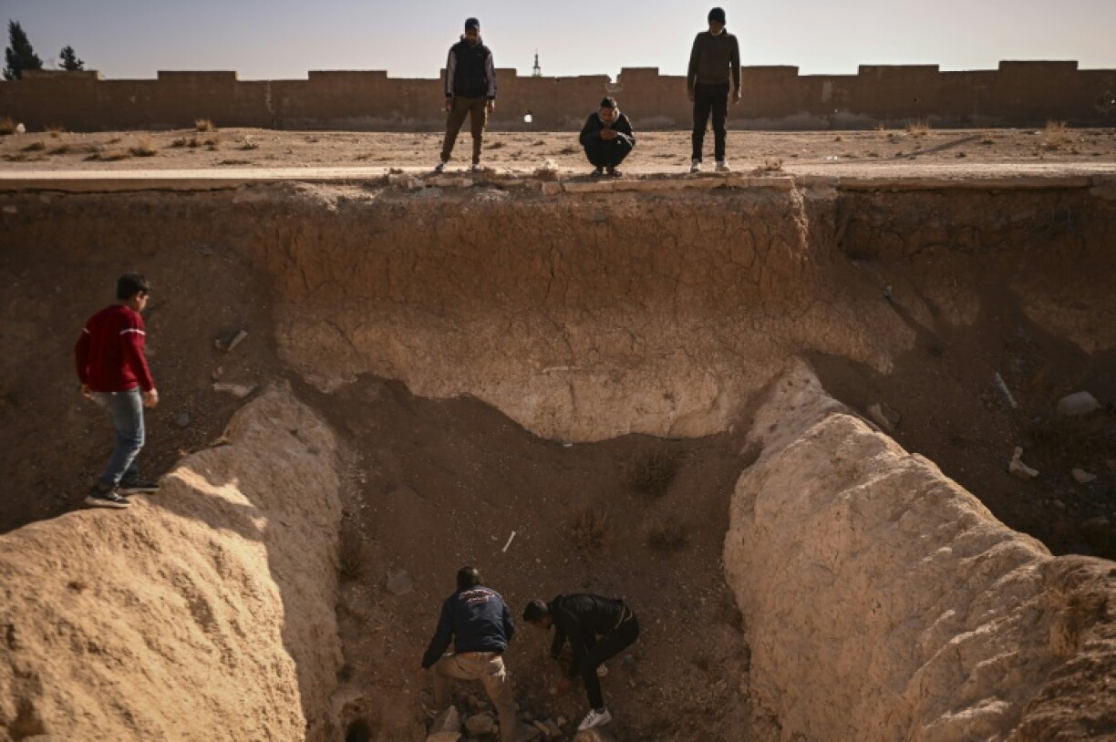 People search for human remains at a trench believed to be used as a mass grave on the outskirts of Damascus