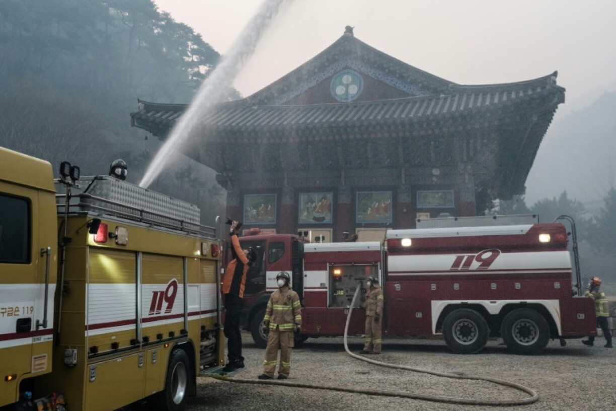 A firefighter controls the water cannon on a fire engine to extinguish the remaining flames after most of the buildings were burned to the ground in a wildfire at Gounsa Temple