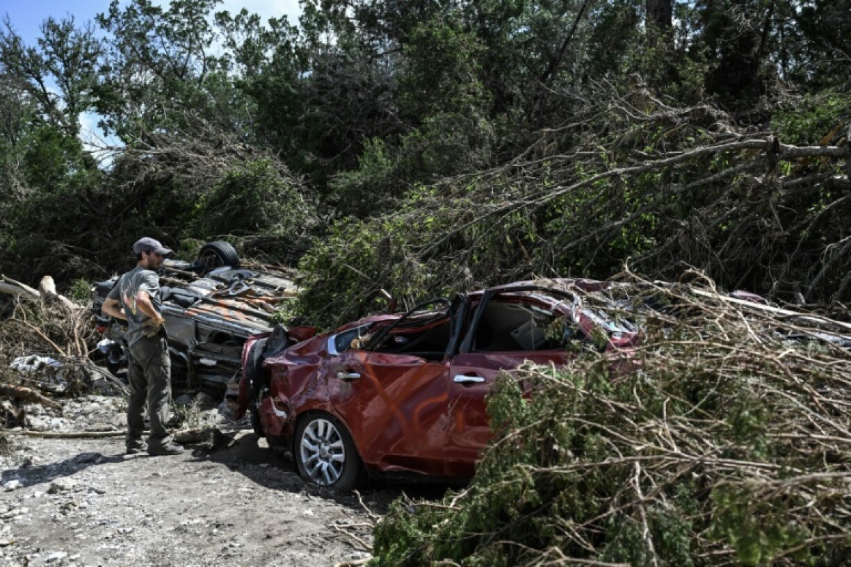 A man searches for missing people by a crushed car near the Guadalupe River in Hunt, Texas