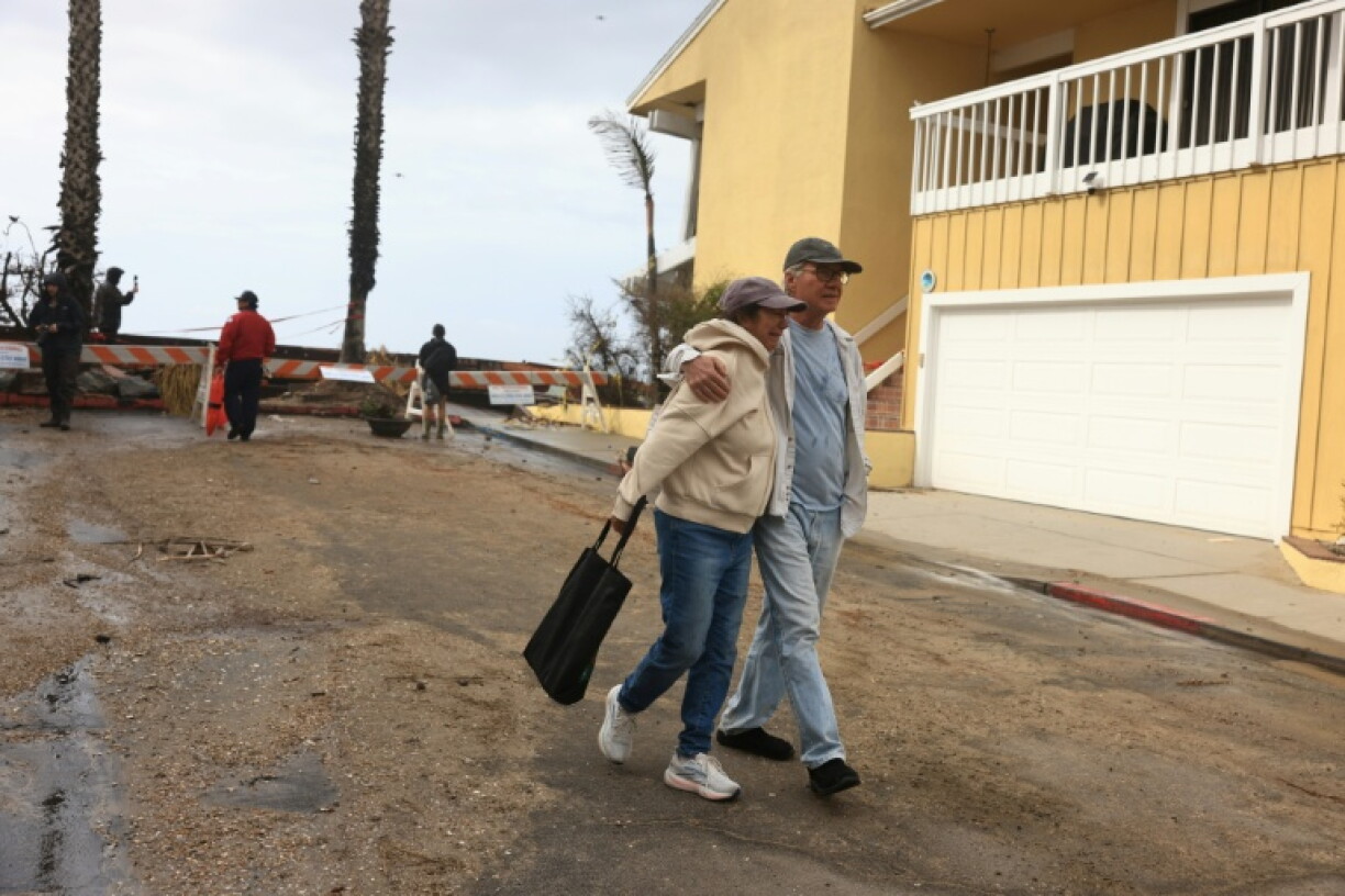 A couple react to storm damage on the boardwalk and homes created by Tropical Storm Rachel in Long Beach, California
