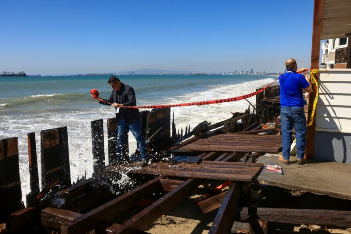 People tape off the damaged boardwalk due to the storm surge in Long Beach, California, where Tropical Storm Rachel could continue to threaten coastal flooding over the weekend