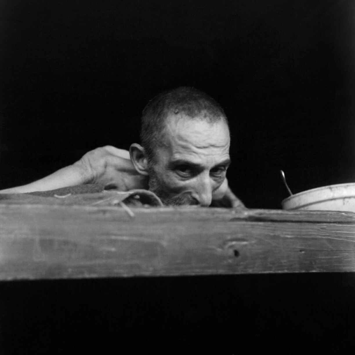 A prisoner dying of dysentery at Buchenwald concentration camp peers out from his bunk in April 1945