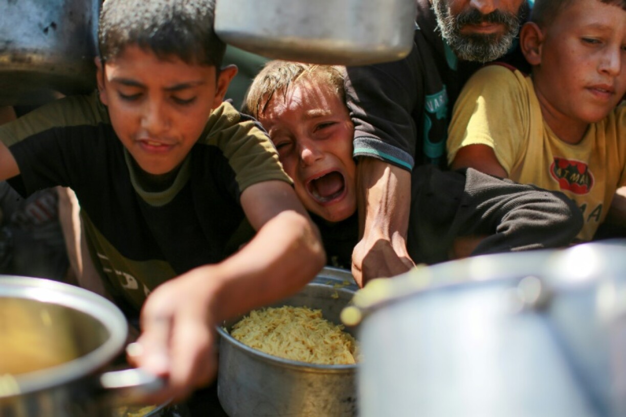 Des Palestiniens attendent d'obtenir du riz auprès d'une soupe populaire dans l'ouest de la ville de Gaza, le 28 août 2025